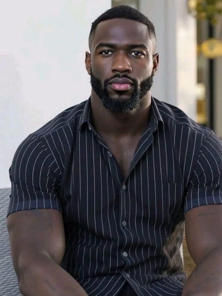 Black man with a groomed short beard wearing a striped black shirt.