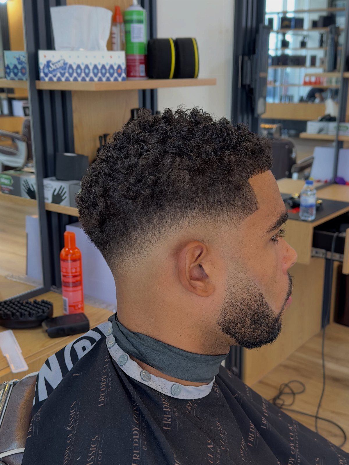 Man with curly hair and a beard showing a fresh skin fade haircut.