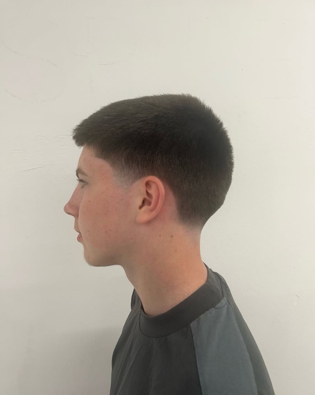 Young man with a short buzzed haircut and straight brown hair in profile.