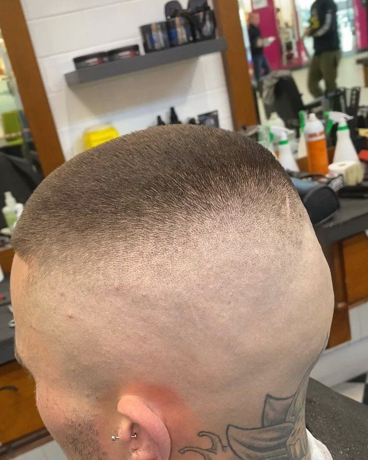Man with a high fade haircut and neck tattoo in a barbershop