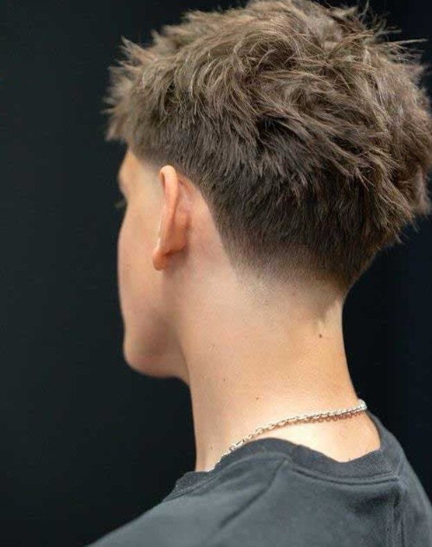 Man with a textured brown low taper fade haircut and silver chain.