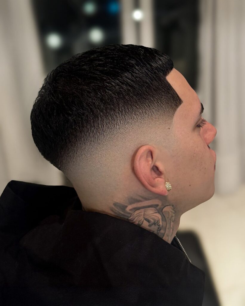 Man with a mid fade haircut and neck tattoo in side profile