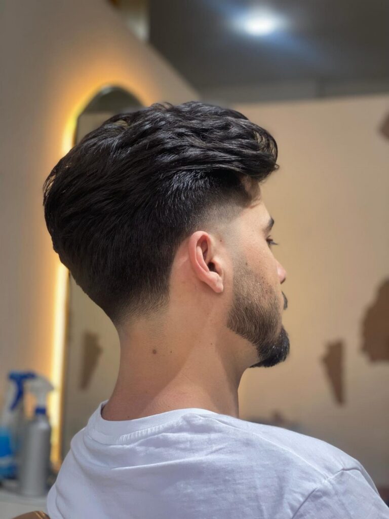 Man with a dark taper fade haircut and groomed beard in profile view